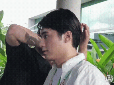 A Man Is Fixing Another Man 'S Hair While Standing Next To A Building . GIF