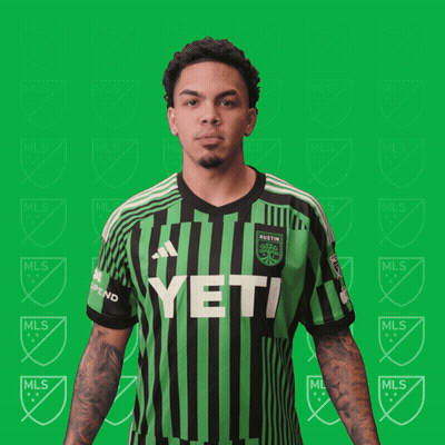 A Man Is Flexing His Muscles In A Green And Black Striped Shirt That Says Yeti GIF