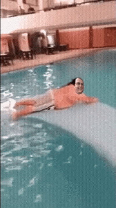 A Man Is Floating On A Raft In A Pool GIF