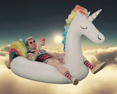 A Man Is Floating On An Inflatable Unicorn GIF