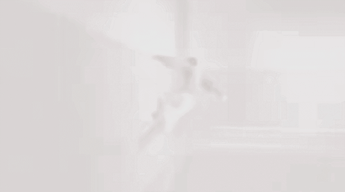 A Man Is Flying Through The Air In A Room GIF