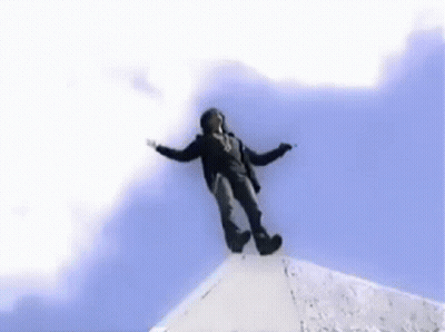 A Man Is Flying Through The Air In Front Of A Large Building GIF