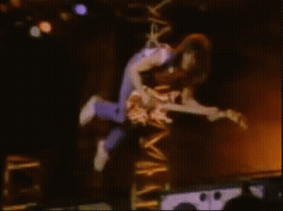 A Man Is Flying Through The Air While Holding A Guitar GIF