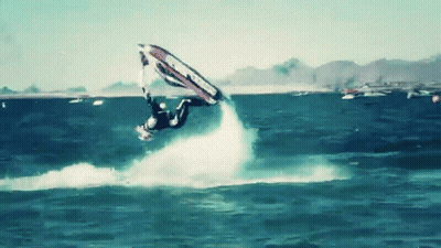 A Man Is Flying Through The Air While Riding A Wave On A Surfboard GIF