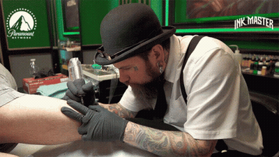A Man Is Getting A Tattoo On Someone 'S Leg In A Paramount Network Tattoo Studio GIF