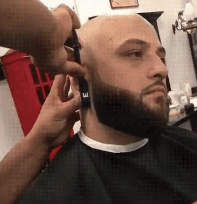 A Man Is Getting His Beard Trimmed By A Barber GIF