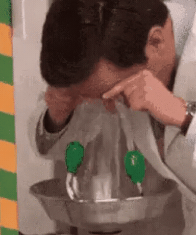 A Man Is Getting His Eyes Rinsed With Water From A Faucet . GIF