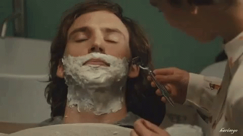 A Man Is Getting His Face Shaved By A Woman In A Bathtub . GIF