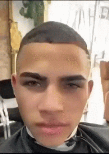 A Man Is Getting His Hair Cut By A Barber In A Salon . GIF