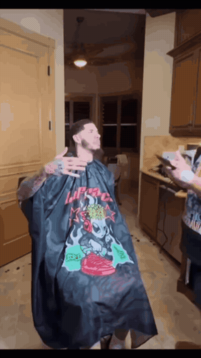 A Man Is Getting His Hair Cut By A Barber Wearing A Black Cape That Says I 'M A Freak GIF