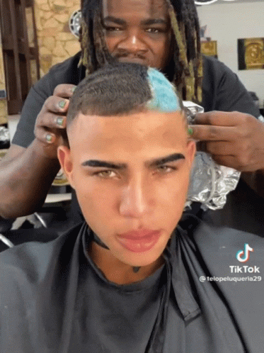 A Man Is Getting His Hair Cut By A Man With Dreadlocks And A Tik Tok Sticker GIF