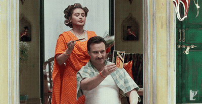 A Man Is Getting His Hair Cut By A Woman With Curlers In His Hair GIF