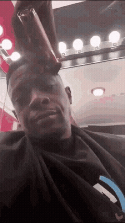 A Man Is Getting His Hair Cut In A Salon . GIF