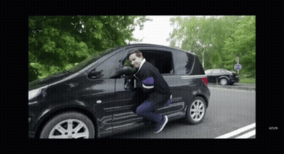 A Man Is Getting Out Of A Black Car With A Stop Sign In The Background GIF