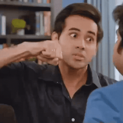 A Man Is Giving A Fist Bump To Another Man In A Living Room . GIF