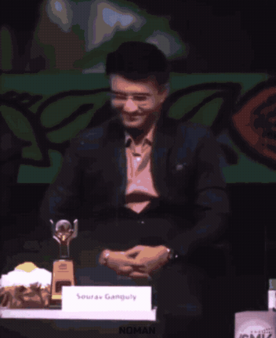A Man Is Giving A Speech At A Podium And The Word Noman Is On The Screen Behind Him GIF