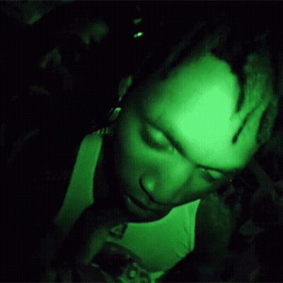 A Man Is Giving The Middle Finger In A Dark Room With A Green Light Behind Him GIF