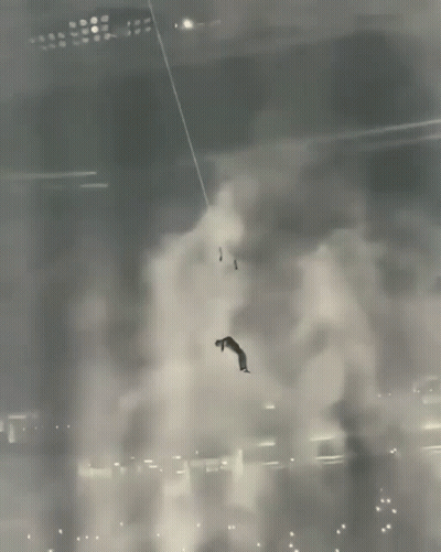 A Man Is Hanging From A Rope In A Dark Room GIF