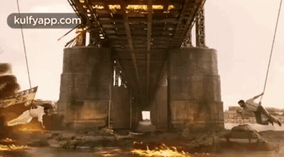 A Man Is Hanging From A Rope Under A Bridge In A Movie Scene . GIF