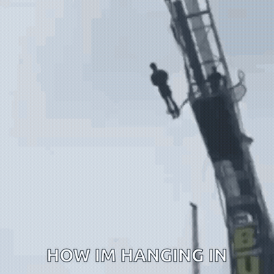 A Man Is Hanging Upside Down From A Bungee Ride . GIF