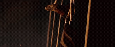 A Man Is Hanging Upside Down With A Golden Mask On His Face . GIF