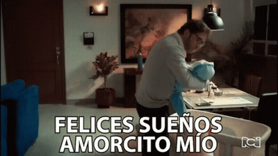 A Man Is Holding A Baby In A Living Room And The Words Felices Suenos Amorcito Mio Are Above Him GIF