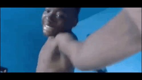 A Man Is Holding A Baby In A Swimming Pool . GIF