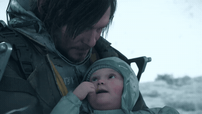 A Man Is Holding A Baby In His Arms And The Baby Is Wearing A Grey Jacket With The Word Columbia On It GIF