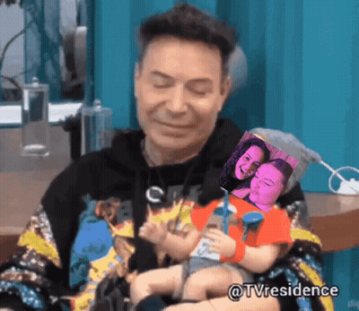 A Man Is Holding A Baby In His Arms With A Picture Of A Woman Behind Him And The Hashtag Tvresidence GIF