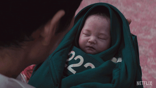 A Man Is Holding A Baby Wrapped In A Green Sweater With The Number 22 On It GIF
