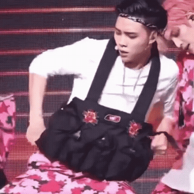 A Man Is Holding A Bag On His Stomach While Dancing On A Stage . GIF