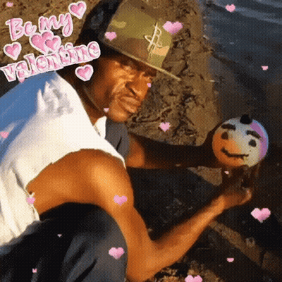 A Man Is Holding A Ball With A Face On It And The Words Be My Valentine Surround Him GIF