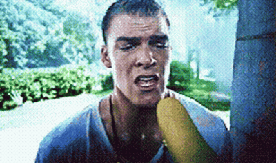 A Man Is Holding A Banana In His Mouth GIF