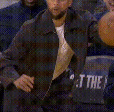 A Man Is Holding A Basketball While Sitting In The Stands . GIF