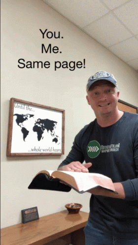A Man Is Holding A Bible In Front Of A Sign That Says " You Me Same Page " GIF