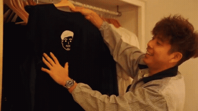 A Man Is Holding A Black Shirt With A Face On It GIF