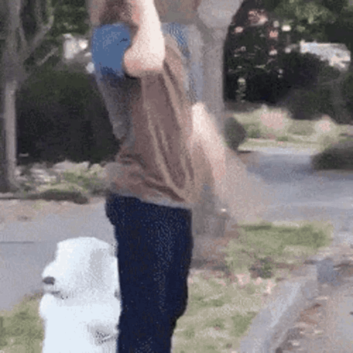 A Man Is Holding A Blue Ball Over His Head While Standing Next To A Fire Hydrant . GIF