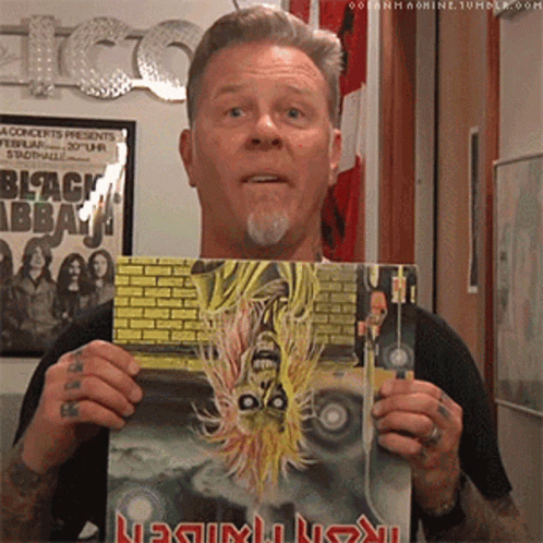 A Man Is Holding A Book That Says Metallica On It GIF