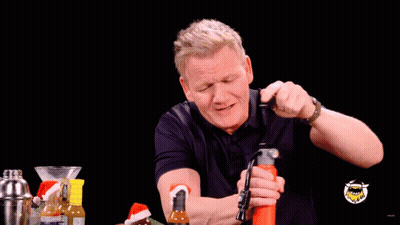 A Man Is Holding A Bottle In His Mouth And Spraying It With His Mouth GIF