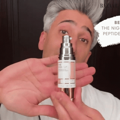 A Man Is Holding A Bottle Of Night Peptide Serum GIF