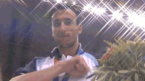 A Man Is Holding A Bouquet Of Flowers In Front Of Him GIF
