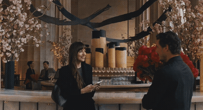 A Man Is Holding A Bouquet Of Red Flowers And A Woman Is Holding A Cell Phone GIF