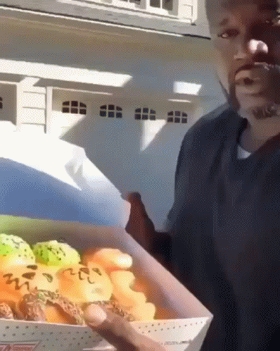 A Man Is Holding A Box Of Donuts With The Number 222 On It GIF