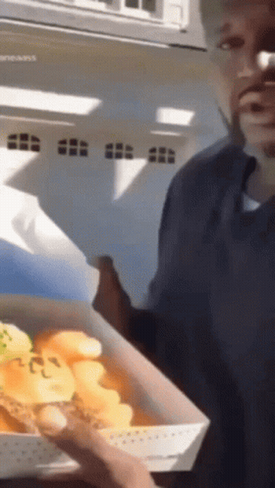 A Man Is Holding A Box Of Food That Says ' Chicken ' On It GIF
