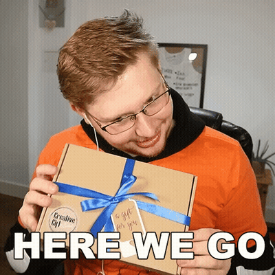 A Man Is Holding A Box With A Blue Ribbon And Says Here We Go GIF