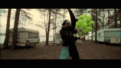 A Man Is Holding A Bunch Of Green Balloons With A Sticker That Says ' A ' On It GIF