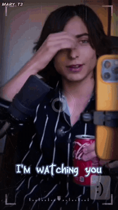 A Man Is Holding A Can Of Coca Cola While Taking A Picture Of Himself . GIF
