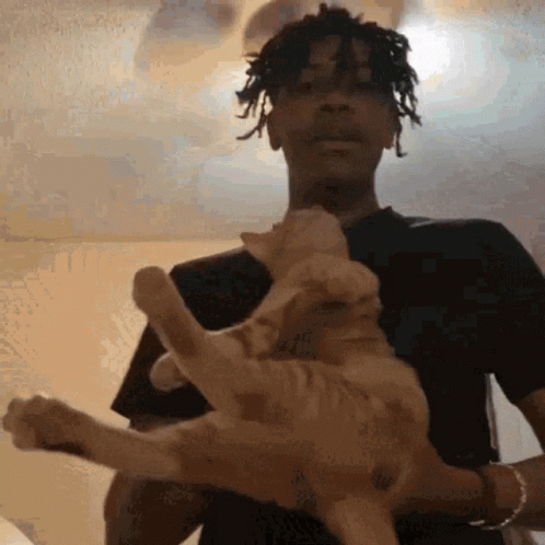 A Man Is Holding A Cat In His Arms GIF