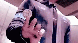 A Man Is Holding A Coin In His Hand And Pointing At It . GIF