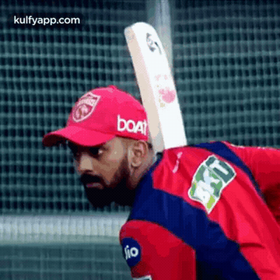 A Man Is Holding A Cricket Bat On His Back . GIF